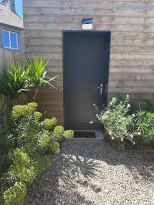 a black door on a wooden wall with plants at Le Cabanon Malouin in Saint Malo