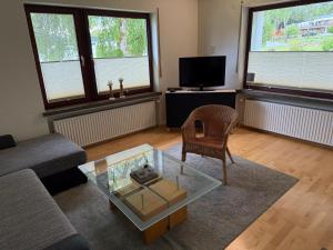 a living room with a couch and a glass coffee table at Haus Eifeldolomiten - Ankommen und Wohlfühlen in Gerolstein