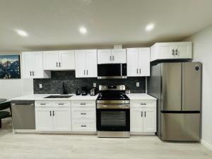 a kitchen with white cabinets and stainless steel appliances at Chic City Escape- come experience tranquility! in Calgary