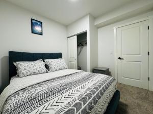 a bedroom with a bed with a black and white comforter at Chic City Escape- come experience tranquility! in Calgary
