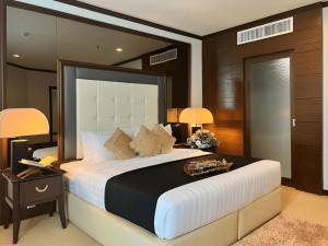 a bedroom with a large bed with a nightstand and lamps at Adya Hotel Kuah Langkawi in Kuah