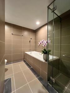 a bathroom with a bath tub and a vase of flowers at Adya Hotel Kuah Langkawi in Kuah