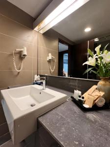a bathroom with a white sink and a mirror at Adya Hotel Kuah Langkawi in Kuah