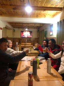 a group of people sitting around a table drinking beer at Hotel Waterfall Benkar in Phakding
