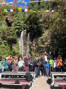 a group of people standing in front of a waterfall at Hotel Waterfall Benkar in Phakding