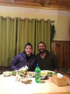 a man and woman sitting at a table with food at Hotel Waterfall Benkar in Phakding