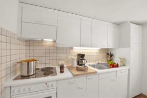 a kitchen with white cabinets and a sink at Rustico Esterina in Val Verzasca for 4 - Happy Rentals in Lavertezzo