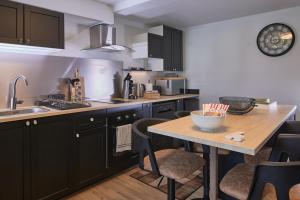 a kitchen with black cabinets and a wooden table at Cinéma Privé Maison Cosy Romantique in Riom