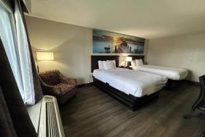 a hotel room with two beds and a chair at Days Inn by Wyndham Savannah Airport in Savannah