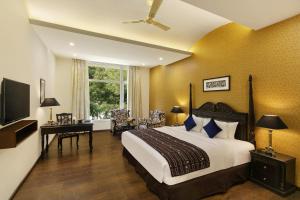 a bedroom with a bed and a desk and a television at Ramada Khajuraho in Khajurāho
