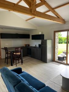 a living room with a blue couch and a kitchen at Le panorama de Canteloup in Fours