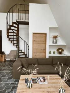 a living room with a couch and a spiral staircase at Nordic Bath Lodge In Normandy in Donnay