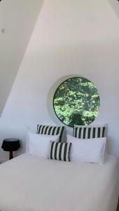 a bedroom with a white bed with a round window at Nordic Bath Lodge In Normandy in Donnay