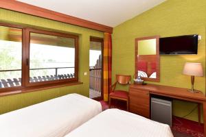 a bedroom with a bed and a desk and a tv at KARPYNĖ Restaurant & Bed & Breakfast in Gabšiai