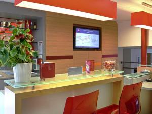 a lobby with a counter with a tv on the wall at Ibis Roscoff Bord de Mer in Roscoff