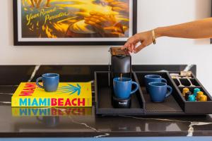 a person holding a coffee maker on a table with blue cups at Hotel Casa Canita in Miami Beach