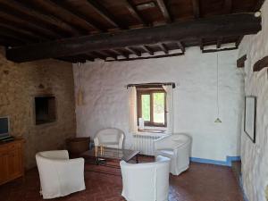 a living room with white chairs and a table and a window at Casa Rural Hosteria Cantarranas in Cuacos de Yuste