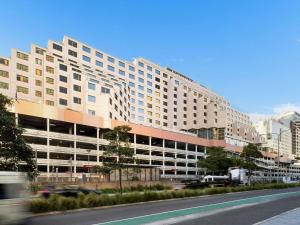 a large white building on a city street with cars at Novotel Sydney Darling Harbour in Sydney