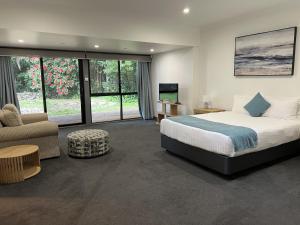 a bedroom with a bed and a couch and a tv at Invercauld House in Goonellabah