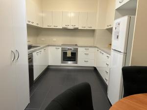 a kitchen with white cabinets and a stove and refrigerator at Invercauld House in Goonellabah