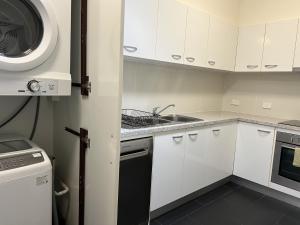 a kitchen with white cabinets and a sink and a microwave at Invercauld House in Goonellabah
