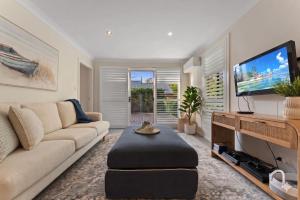 a living room with a couch and a flat screen tv at Flannel Flower Beach House in Shoal Bay