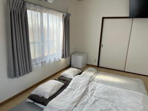 a bed with two pillows in a room with a window at 아라무사aramoosa민숙 in Tsushima