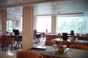 a restaurant with tables and chairs and a large window at Hotel The Amrit in Jabalpur
