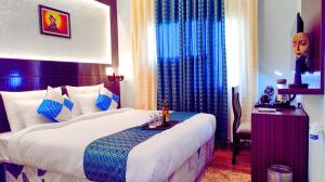 a hotel room with a large bed and a table at Asapian Vanyamahal - A Nature Resort in Rāmnagar