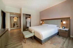 a bedroom with a large white bed and a bathroom at Hyatt Regency Panama City in Panama City