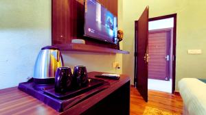 a room with a coffee maker and a television at Asapian Vanyamahal - A Nature Resort in Rāmnagar