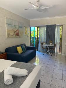 a living room with a blue couch and a table at Tropical Palms Resort & 4WD Hire in Picnic Bay