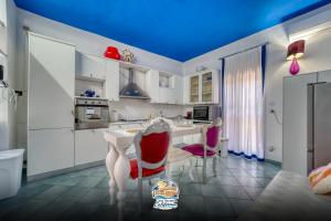 a kitchen with white cabinets and red chairs at Casa Vacanza California in Bari