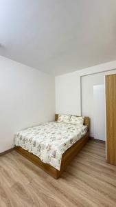 a bed in a white room with a wooden floor at LeeThuyhomePR86 in Kinh Dinh
