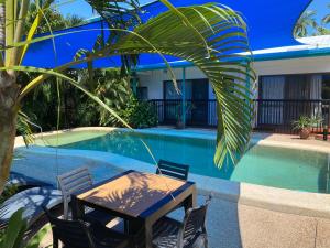 a table and chairs next to a swimming pool at Tropical Palms Resort & 4WD Hire in Picnic Bay