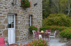 a patio with a table and chairs in front of a stone building at Hostellerie de la Motte jean in Saint-Coulomb