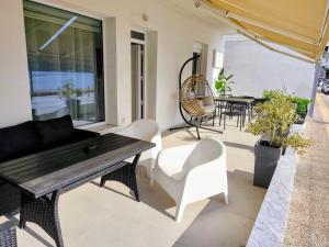 a patio with a wooden table and white chairs at Aurora suite in Nea Peramos