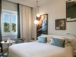 ein Schlafzimmer mit einem großen weißen Bett und einem Tisch in der Unterkunft Sofitel Roma Villa Borghese in Rom + 274 Fotos