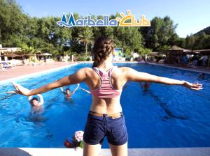 Una mujer parada en una piscina con los brazos extendidos en Villaggio Marbella Club, en Palinuro