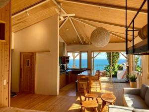 an open living room and dining room with a view of the ocean at 丘の上の小さなスローリゾート フェニックスの宿 in Miyazaki