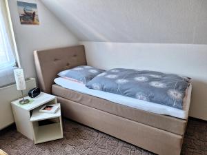 a bed with a blue comforter and a side table at Willkommen bei Renate und Jörg in Unna