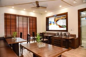 a restaurant with tables and chairs and a painting on the wall at Hotel Grand In Near 2 Min From Vaishali Metro Station in Ghaziabad