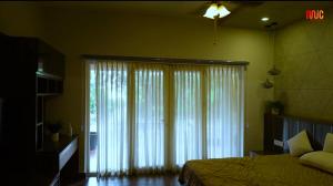 a bedroom with a bed and a large window with curtains at Mannath Lake House in Murinjupuzha
