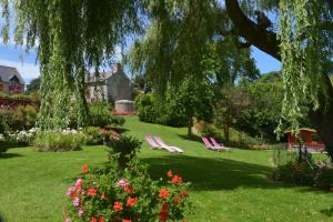 two lawn chairs and flowers in a garden at Hostellerie de la Motte jean in Saint-Coulomb