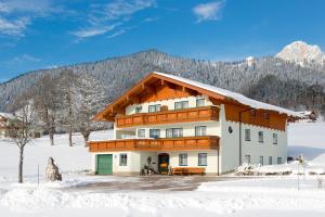 a building in the snow with mountains in the background at Pernerhof in Ramsau am Dachstein