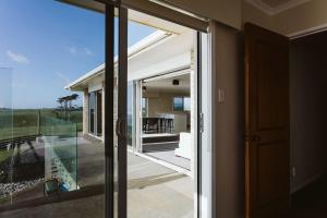 an open sliding glass door to a patio with a view at ABC on Wanaka Bay - beachfront home w. ocean views in New Plymouth