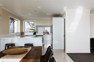 a kitchen with white cabinets and a wooden table at ABC on Wanaka Bay - beachfront home w. ocean views in New Plymouth