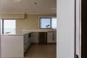 a kitchen with white counters and windows and a counter top at ABC on Wanaka Bay - beachfront home w. ocean views in New Plymouth +13 photos