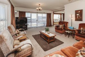a living room with couches and a tv and a table at Beach House On Hamblyn in New Plymouth