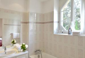 a bathroom with a tub and a sink and a window at Hostellerie de la Motte jean in Saint-Coulomb